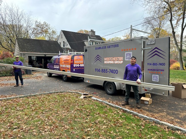 Westchester Roofing workers standing outside of the company truck holding a long gutter piece